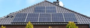 Solar panels on the roof of a new home against a blue sky.