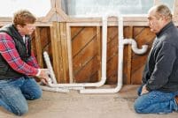 Kevin O'Connor and Richard Trethewey look at PVC pipes that are part of a plumbing project.