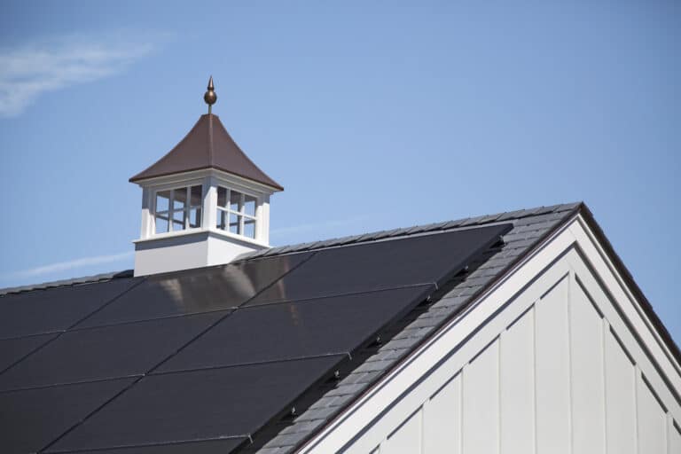 Close-up shot of a roof with solar panels on it and a blue sky in the background